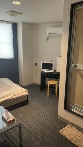 a room with a bed and a desk with a microwave at はらビジネス旅館 in Wakayama