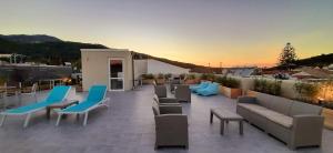 a rooftop patio with couches and chairs and a sunset at The Central Villa - Kassiopi Corfu Villas in Kassiopi