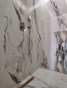 een badkamer met een douche en een marmeren muur bij Aurora Hills Hotel in Plovdiv