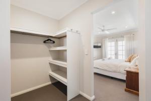 1 dormitorio con paredes blancas, 1 cama y estanterías en AZZURE on WATERVILLE, en Dunsborough