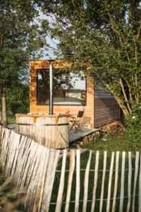 una pequeña casa con una valla en un patio en La cabane de la Ferme du Ry en Sorinnes