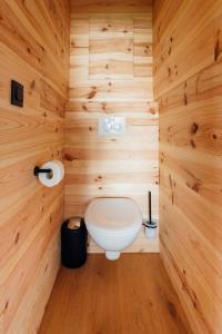 a bathroom with a toilet in a wooden wall at La cabane de la Ferme du Ry in Sorinnes