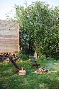 dwa krzesła i miejsce na ognisko w trawie w obiekcie La cabane de la Ferme du Ry w mieście Sorinnes