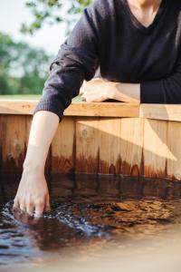 a person reaching into the water from a wooden box at La cabane de la Ferme du Ry in Sorinnes