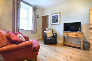 a living room with a couch and a tv and a chair at Farne View Cottage in Seahouses