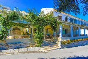 Una casa amarilla con un árbol delante. en Theophilos Ena, en Ágios Stéfanos