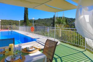 un patio con mesa y sillas junto a una piscina en Cochelli Upper Pool Walk to beach AC WiFi, en Ágios Stéfanos