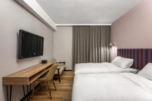 a hotel room with two beds and a desk and a tv at River Inn Kenting in Hengchun