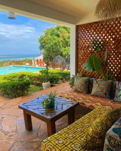 a patio with a table and a couch and the ocean at FURAHA VILLA 3 in Chanjani