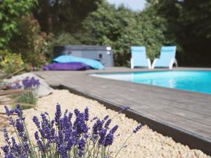 una piscina con due sedie blu e fiori viola di Chambres d'Hotes - La Marmoire a Soudan