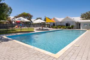 a swimming pool with chairs and umbrellas next to a house at 5@CapeView, beachfront Geographe Bay in Busselton