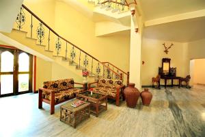 ein Wohnzimmer mit Sofas und einer Treppe in der Unterkunft Hotel Chandrawati Palace in Ābu Road
