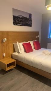 um quarto com 2 camas com almofadas vermelhas e brancas em Eazy apartments em Newcastle upon Tyne