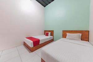two beds in a room with white walls at RedDoorz near UNSIKA University Karawang in Karawang