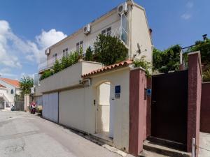 a white building with a gate and a garage at Apartment Olga in Dubrovnik