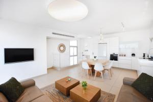a white living room with a table and a kitchen at Skylight 3BR in Bograshov by HolyGuest in Tel Aviv