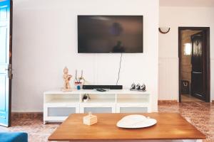 sala de estar con mesa y TV en la pared en Casa Mar adentro, en La Santa