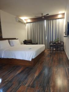 a bedroom with a bed and a chair and a table at GReaT trails yercaud by GRT Hotels in Yercaud