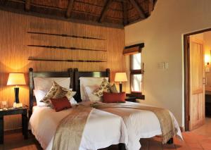 een slaapkamer met een bed met witte lakens en rode kussens bij Madikwe River Lodge by Dream Resorts in Madikwe Wildreservaat