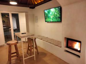 uma sala de estar com lareira e uma televisão na parede em Casa Cueva El Naranjo Rocabella em El Chorro