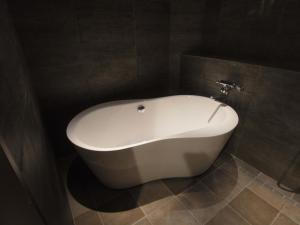 un bagno con vasca bianca e pareti piastrellate di ホテルラパンセ Adult Only a Saitama