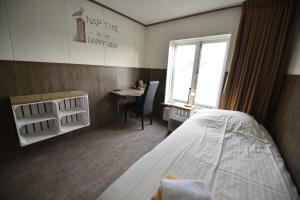 um quarto com uma cama, uma secretária e uma janela em Havenzicht em Dinteloord