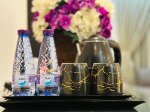 Tres botellas y dos vasos en una bandeja con flores. en Shada Residence Hotel en Al Khobar
