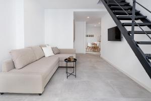un soggiorno bianco con divano e scala di BHost - Regina III a Cordoba Altre 10 foto