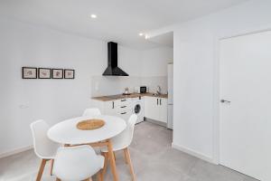 una cucina bianca con tavolo e sedie bianchi di BHost - Regina III a Cordoba