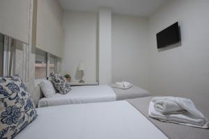 Habitación blanca con 2 camas y TV. en Carreteria 73 Malaga Center, en Málaga