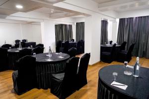 a room with black tables and chairs and windows at TGI Ameya Grand in Old Goa