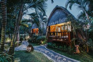 une maison dans un jardin planté de palmiers dans l'établissement Alam Nusa Bungalow Huts & Spa, à Nusa Lembongan
