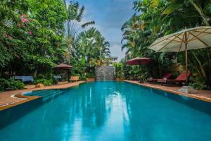 a pool at a resort with trees and umbrellas at Marirath Boutique Hotel in Siem Reap