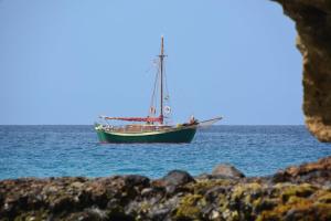 a boat floating in the water near the shore at Bungalow Marietta in Vila do Maio