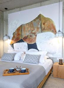 1 dormitorio con 1 cama con una pintura en la pared en Marnos Luxury Villas en Kamilari