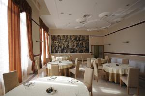 a dining room with white tables and chairs and a mural at Hotel Royal in Senta