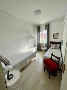 a bedroom with two beds and a red chair at Your Familyapartment in Sirmione in Sirmione