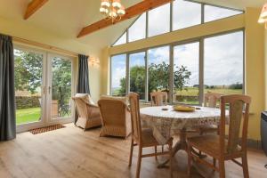 a dining room with a table and chairs and windows at Rose Cottage Elsdon in Elsdon