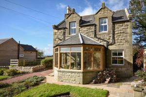 a house with a conservatory on the front of it at The Lodge Elsdon in Elsdon