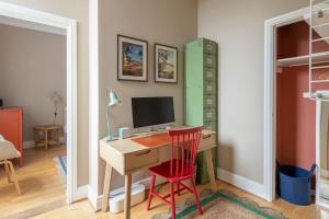 a room with a desk with a computer and a red chair at Stylish Central Apartment with Parking - Garden and Workspace in Bath