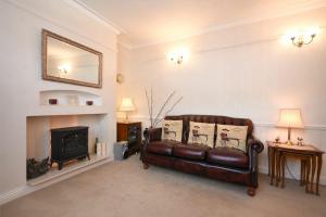 a living room with a leather couch and a fireplace at Seaview Cottage Amble in Amble