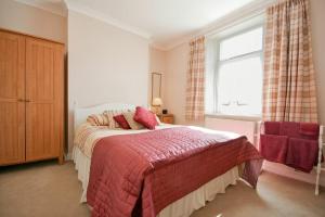 um quarto com uma cama com um cobertor vermelho e uma janela em Seaview Cottage Amble em Amble