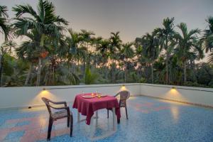 a table and chairs on a balcony with palm trees at Hotel Snehaprabha - Near to Nagaon Beach Alibaug in Alibaug