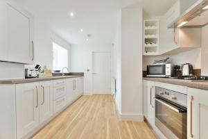 a kitchen with white cabinets and a wooden floor at The Lodge Alnwick in Alnwick