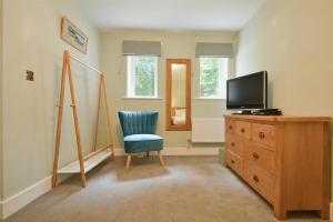 a room with a tv and a chair and a dresser at The Lodge Alnwick in Alnwick