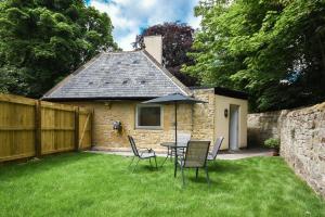 a table and chairs with an umbrella in a yard at The Lodge Alnwick in Alnwick