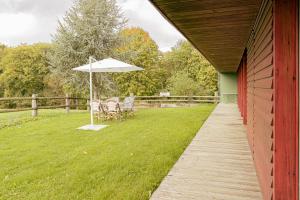 a porch with a table and an umbrella at La Maison des Bois in Bagnoles de l'Orne