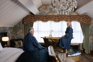 a man and woman standing in a bedroom with a tub at The Old Inn in Crawfordsburn