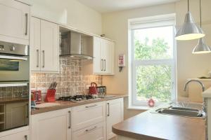 una cocina con armarios blancos y una ventana en St Julians, en Alnmouth
