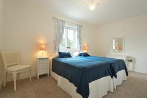 a bedroom with a blue bed with a chair and a window at Two Castles in Bamburgh